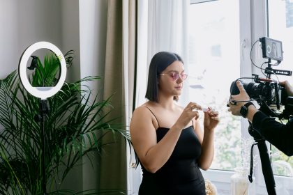 Criadora grava uma avaliação de produto em ambiente interno, diante de uma câmera e de uma luz circular.